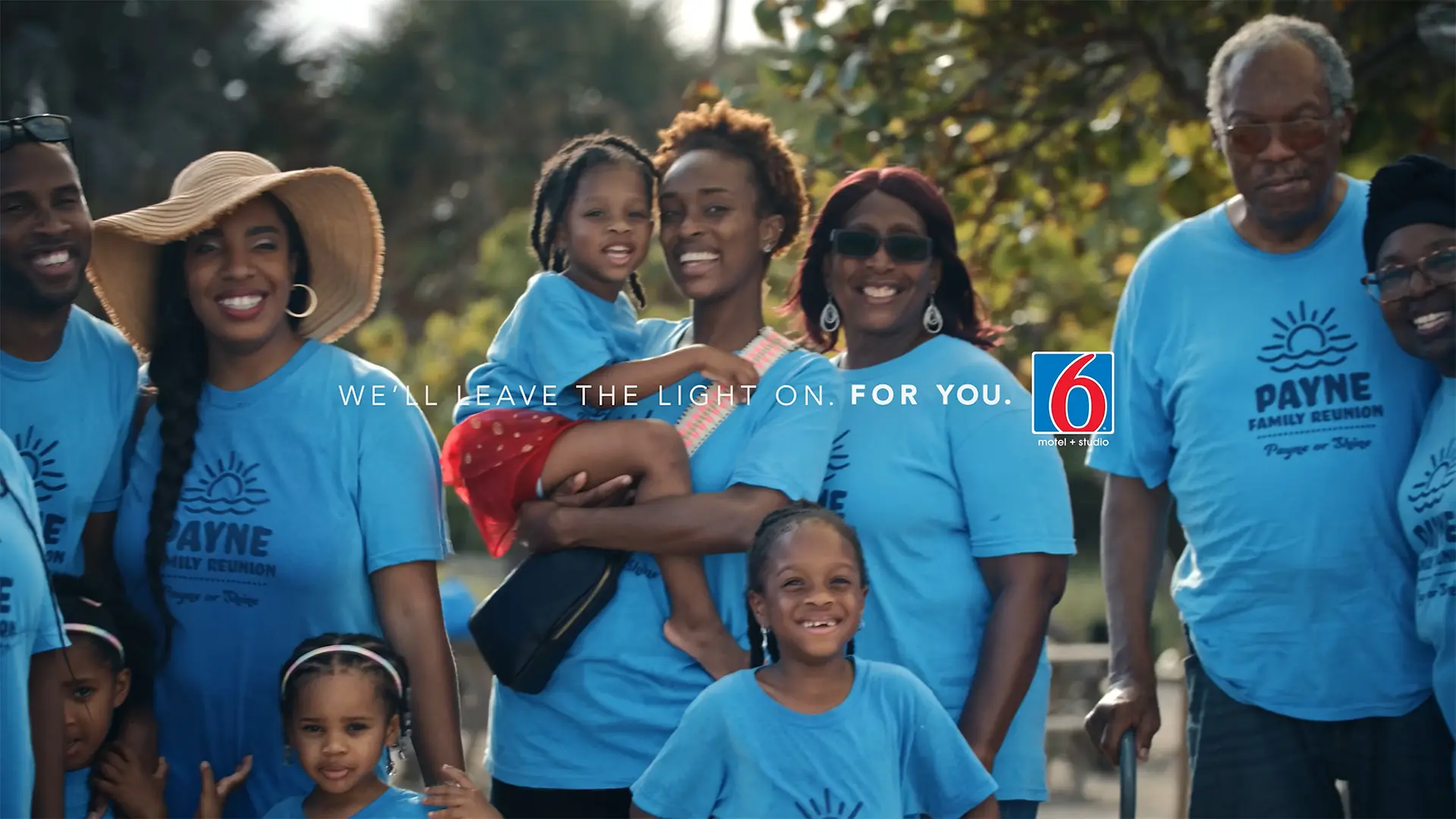 men and women of all ages gather for the Payne Family Reunion, with the Motel 6 logo 