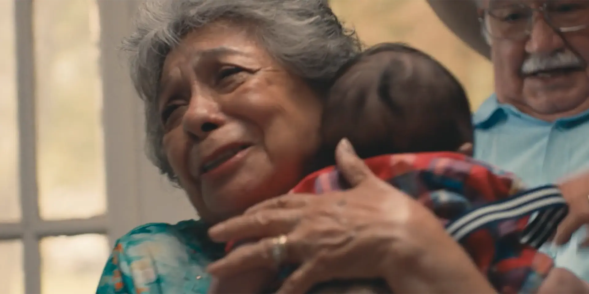 a grandmother and grandfather hugging their newly-born grandchild