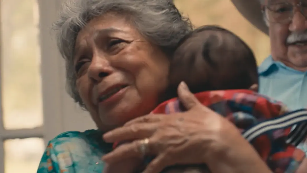 a grandmother and grandfather hugging their newly-born grandchild