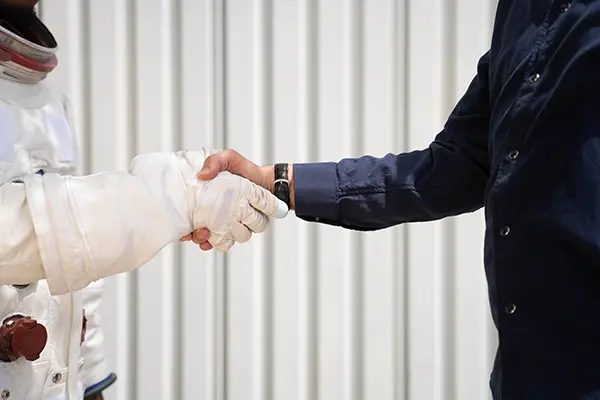 a man in a business suit shaking hands with a man in a space suit