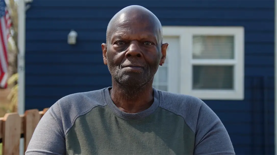 a veteran in close-up, standing in front of a house