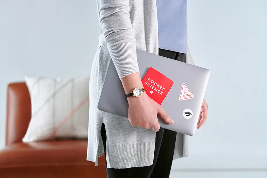 a BarkleyOKRP employee holding a laptop covered with stickers